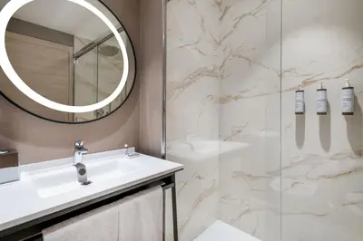 a bathroom with a sink and a mirror and a shower at AC Hotel by Marriott Clodio Roma in Rome