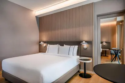 a bedroom with a large white bed and a table at AC Hotel by Marriott Clodio Roma in Rome