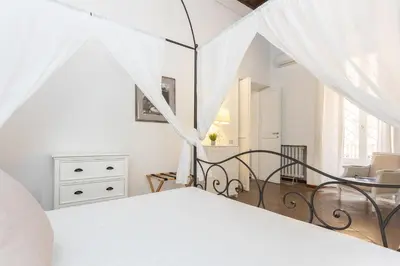 a white bedroom with a bed with white curtains at Rental in Rome - Bramante Luxury in Rome