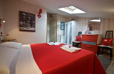 a bedroom with a red and white bed and a chair at Alma de Roma in Rome