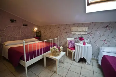 a bedroom with two beds and a table with flowers at Alma de Roma in Rome
