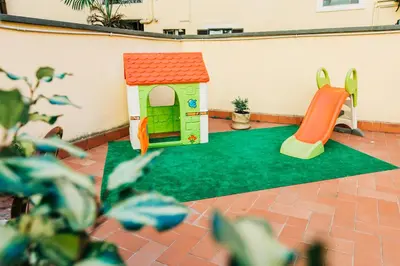 a play area with a toy house and a slide at La Vite Vaticana in Rome