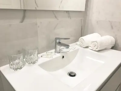 a white bathroom sink with two glasses and towels at B&B Palombini in Rome