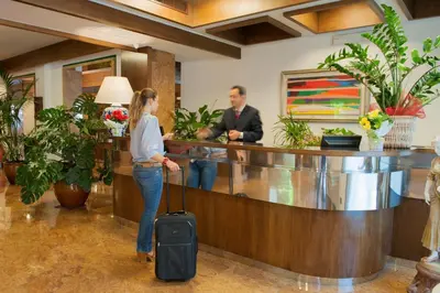 a woman with a suitcase in a lobby with a man at Hotel La Pergola in Rome