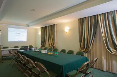 a conference room with a green table and chairs at Ateneo Garden Palace in Rome