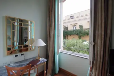 a room with a desk with a mirror and a window at Ateneo Garden Palace in Rome