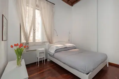 a white bedroom with a bed and a window at Antique-Modern Flat by Navona Square in Rome