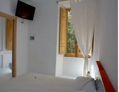 a white bedroom with a bed and a window at A Casa Di Penelope in Rome