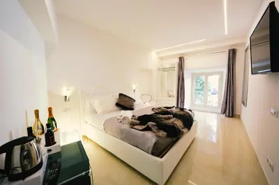 a white bedroom with a bed and a television at San Pietro Grand Suite in Rome