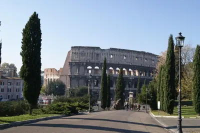 a street in front of a large building with trees at Tatusa al Colosseo in Rome