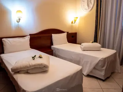two beds in a hotel room with white sheets at Caroline Suite in Rome