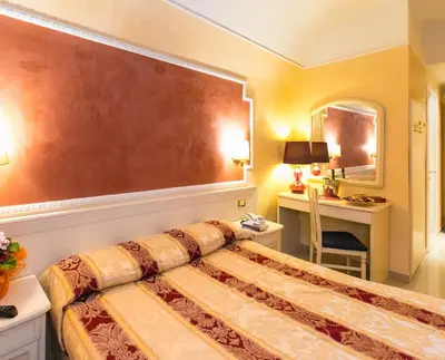 a bedroom with a bed and a desk and a mirror at Hotel Erdarelli in Rome