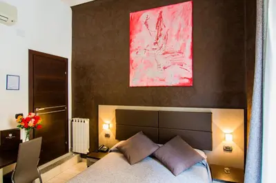 a bedroom with a bed with a pink painting above it at Hotel Charter in Rome