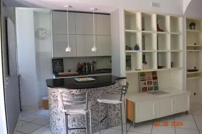 a kitchen with white cabinets and a black counter top at Trastevere St. Garden House in Rome