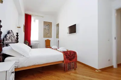 a bedroom with a white bed with a red curtain at Sistina in Rome