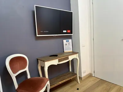 a tv on a wall with a table and a chair at Roma Chic Flat Monte Mario in Rome