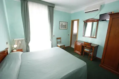 a bedroom with a bed and a desk and a window at Hotel Adriatic in Rome