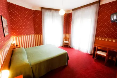a bedroom with a bed and two windows and a desk at Hotel Adriatic in Rome
