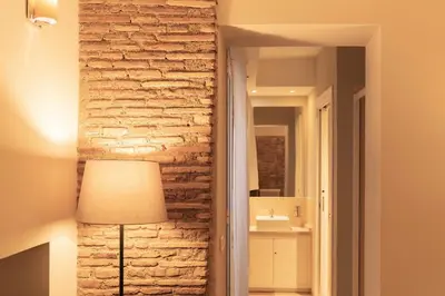 a living room with a brick wall and a lamp at TrastevereInn in Rome