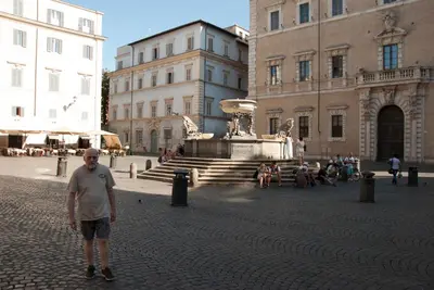 a man standing in front of a building with a fountain at Trastevere classico self check in in Rome