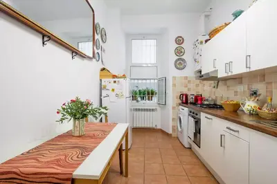 a kitchen with white cabinets and a table with flowers on it at Trastevere classico self check in in Rome