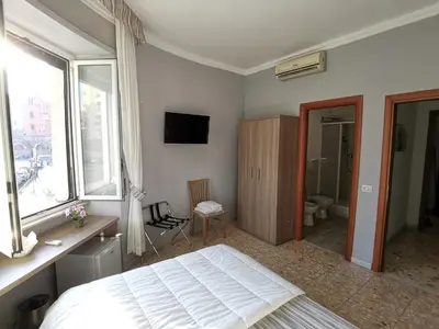 a bedroom with a bed and a bathroom with a window at St. Anthony Guest House in Rome