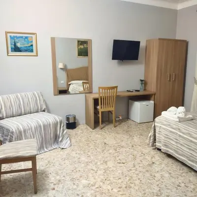 a living room with a couch and a desk with a mirror at St. Anthony Guest House in Rome