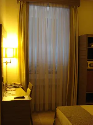 a bedroom with a bed and a desk with a window at Morrisson Exclusive Rooms in Rome