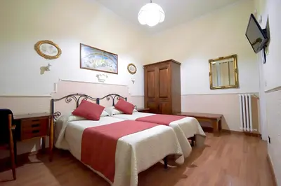 a bedroom with two beds with red and white sheets at Hotel Alexis in Rome