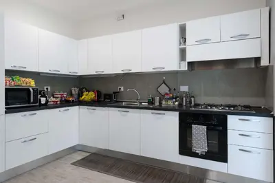 a white kitchen with white cabinets and a sink at M&M House in Rome