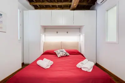 a bedroom with a red bed with two towels on it at Piazza Navona-Coronari House in Rome