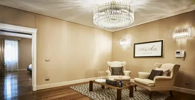 a living room with two chairs and a chandelier at LE RÊVE DE NAIM Roma in Rome