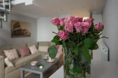 a vase of pink roses on a table in a living room at Frankie Charme in Rome