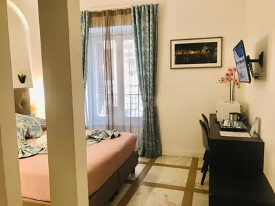 a bedroom with a bed and a desk and a window at KAMBAL LUXURY SUITES in Rome