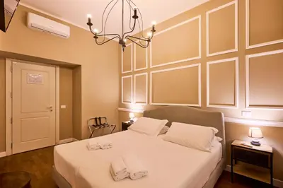 a bedroom with a bed with white sheets and a chandelier at DEM Hotel in Rome