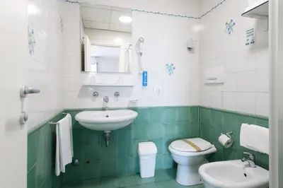 a green and white bathroom with a sink and a toilet at Hotel Casa Tra Noi in Rome