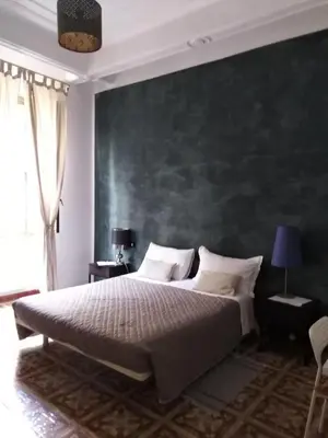 a bedroom with a large bed with a green wall at Trastevere Corner Eight in Rome