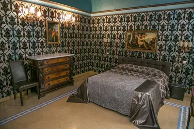 a bedroom with a bed and a dresser and wallpaper at Antica Dimora De Michaelis in Rome