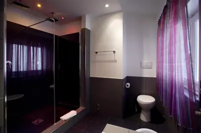 a bathroom with a toilet and a glass shower at Town House Fontana Di Trevi in Rome