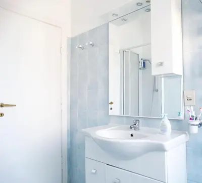 a white bathroom with a sink and a mirror at By Grace in Rome