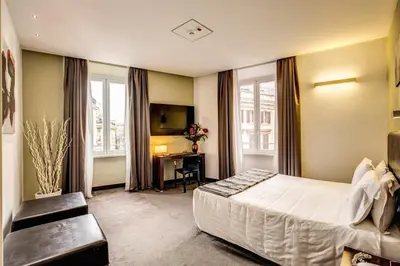 a bedroom with a bed and a desk and windows at Trevi Collection Hotel - Gruppo Trevi Hotels in Rome