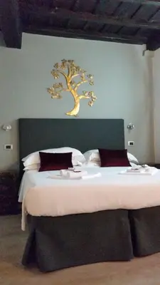 a bedroom with a bed with a tree on the wall at Navona First Rooms in Rome