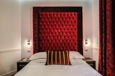 a bedroom with a red padded headboard and a bed at La Foresteria Luxury Suites in Rome