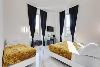 a white bedroom with two beds and windows at St. Peter Grand Suite in Rome