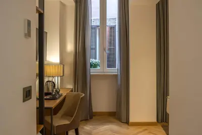 a room with a desk and a window with a table at Navona Essence Hotel in Rome