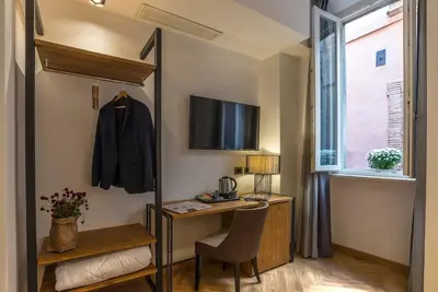 a small room with a desk and a table with a chair at Navona Essence Hotel in Rome