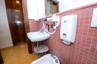 a pink tiled bathroom with a sink and a toilet at Aelius in Rome