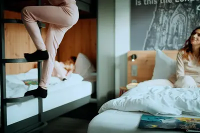 a woman is sitting on a bunk bed at MEININGER Roma Termini in Rome