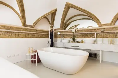 a bathroom with a white tub and gold wallpaper at Experience Collection by ROMAC - Costaguti Experience in Rome