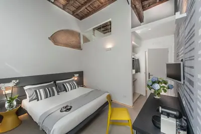 a bedroom with a large bed and a yellow chair at First Floor - Boutique Hotel in Rome